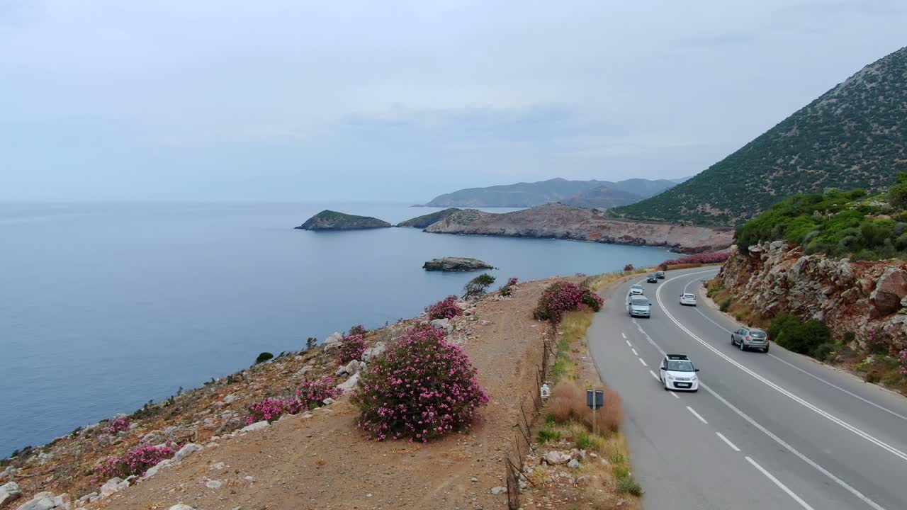 Traffic drives along curving highway along the coast of Crete