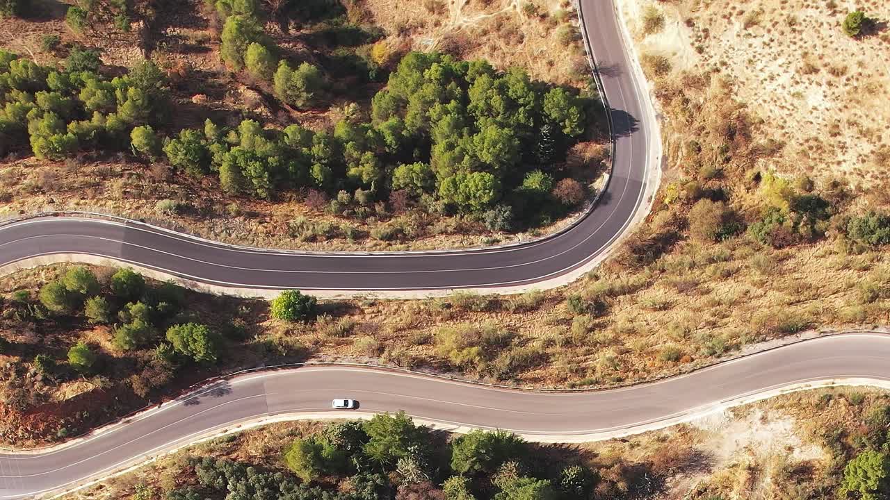 Strada tortuosa tra le colline vicino a Granada, Spagna, con alberi ed erba