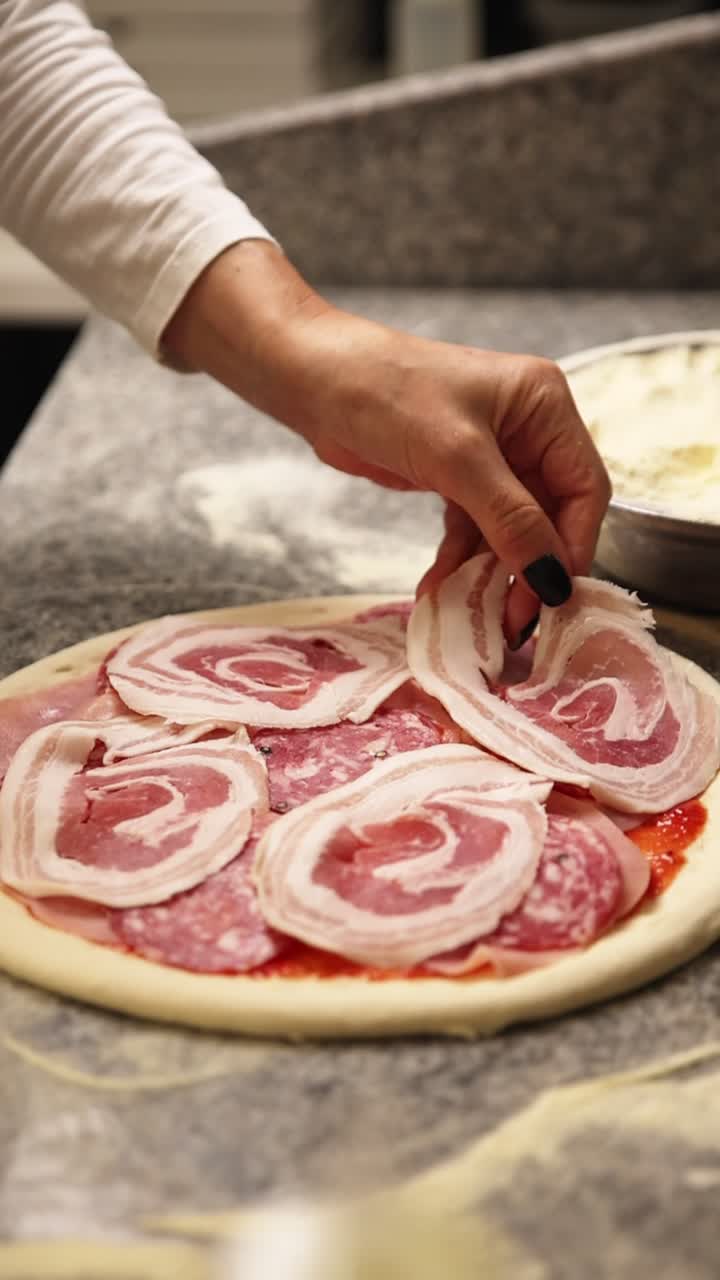 Chef's Hand Placing Slices of Meat on a Raw Pizza Dough