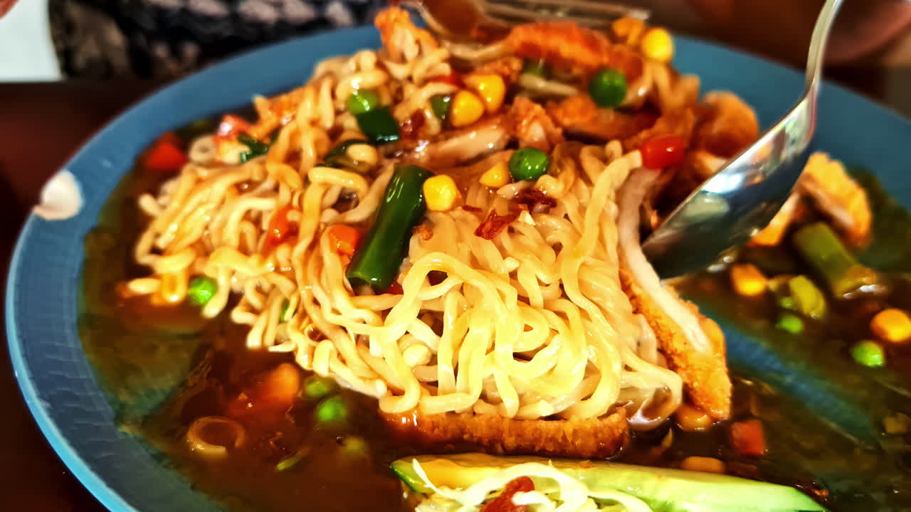Noodles with chicken and vegetables served in a bowl with chopsticks in Bali