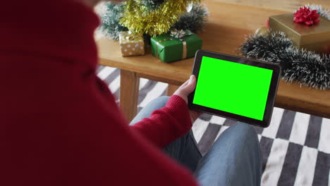 caucasian man in santa hat making tablet christmas video call, with green screen