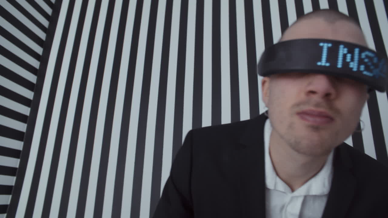 Man wearing VR headset with digital display, in front of striped background