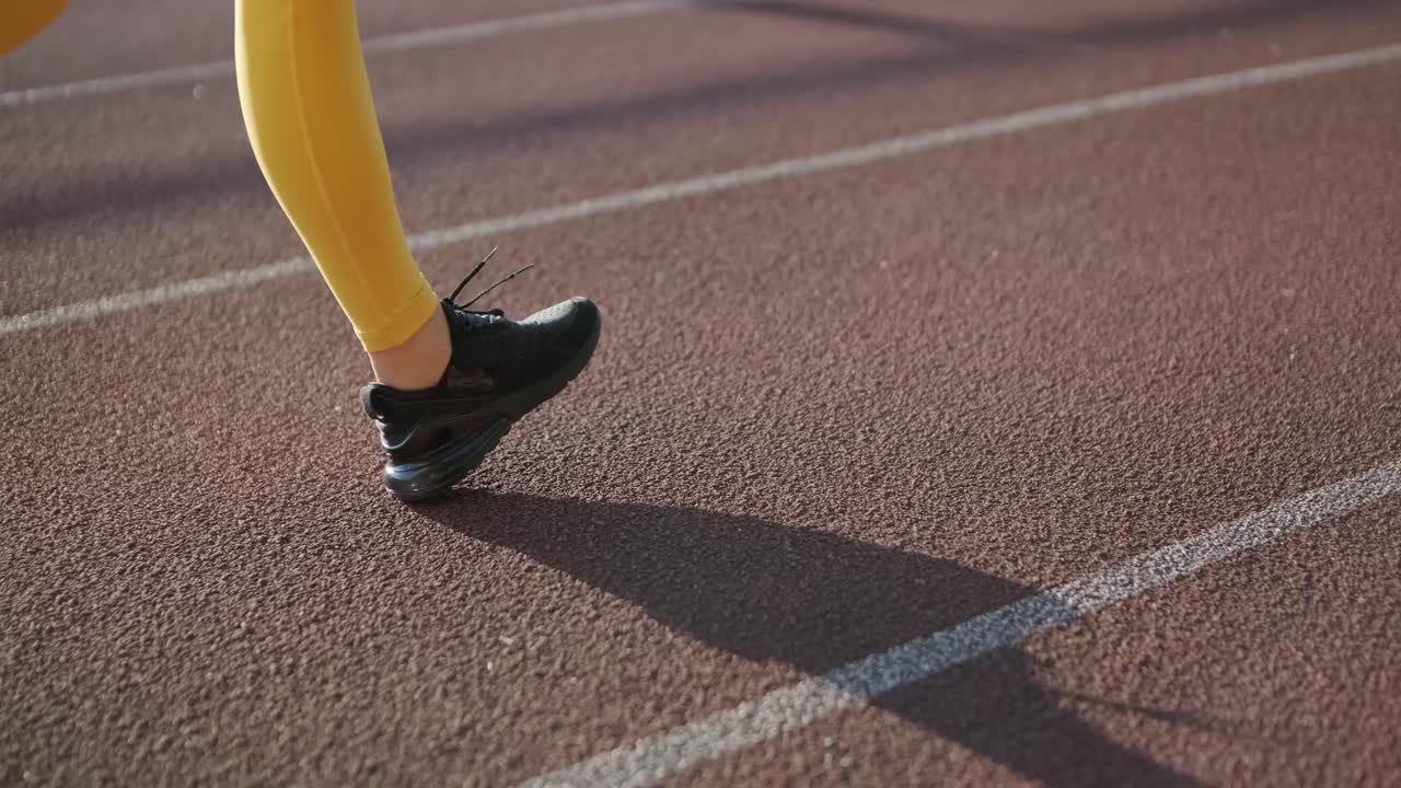 Donna che fa jogging su pista all'aperto in abbigliamento sportivo in un campo di atletica