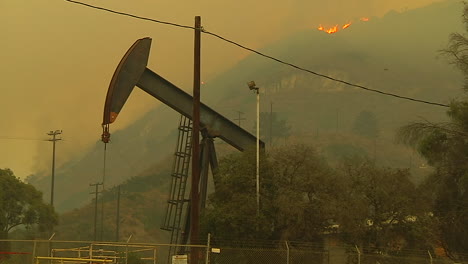 the hills behind an oil derrick between ventura and santa barbara burn during the thomas fire