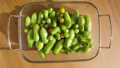 tomates orgánicos verdes que maduran dentro de una canasta de metal a la luz del sol