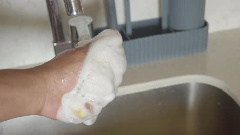 person washing dishes in kitchen sink