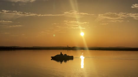 A-boat-in-the-middle-of-the-Nile-river-at-sunset,-wide-shot,-static-shot