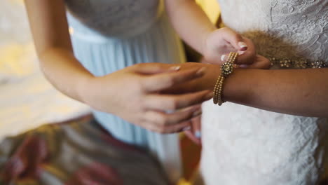 dama de honor poniendo un hermoso brazalete en la muñeca de la novia