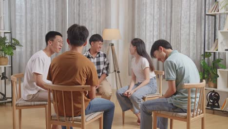 asian teen group sitting in chairs forming a circle enjoy discussing at home