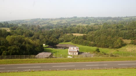 wide shot of carsington water treatment works with the dam road foreground with cars passing through frame