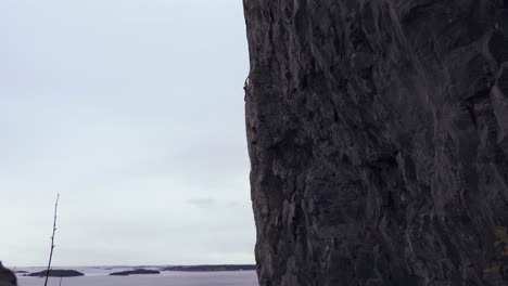 shot of a man vertically climbing up a large mountain