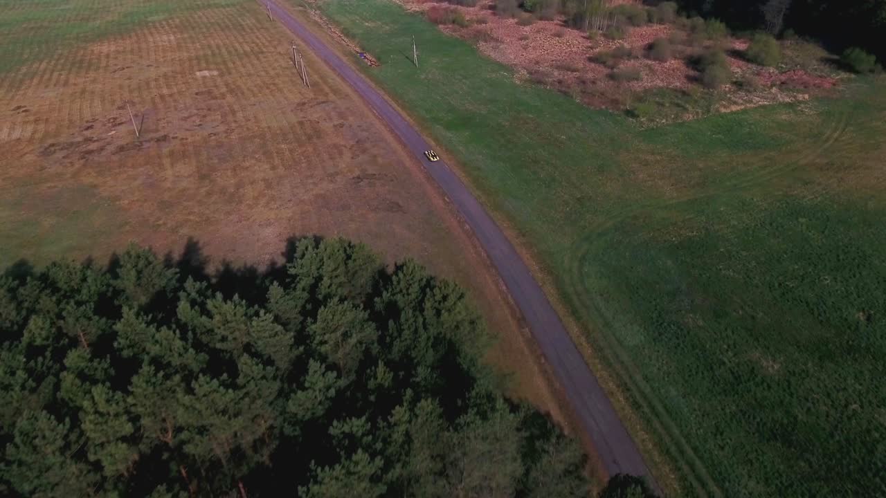 Aerial view of a road through a forest and field landscape