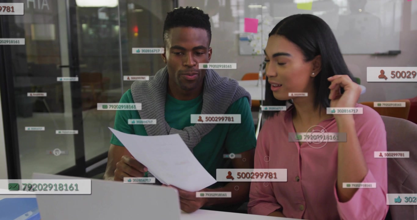 Dua rekan bisnis meninjau lembar sambil membungkuk di atas laptop, mengangkat kertas menyebabkan tag UI melonjak lalu memudar.