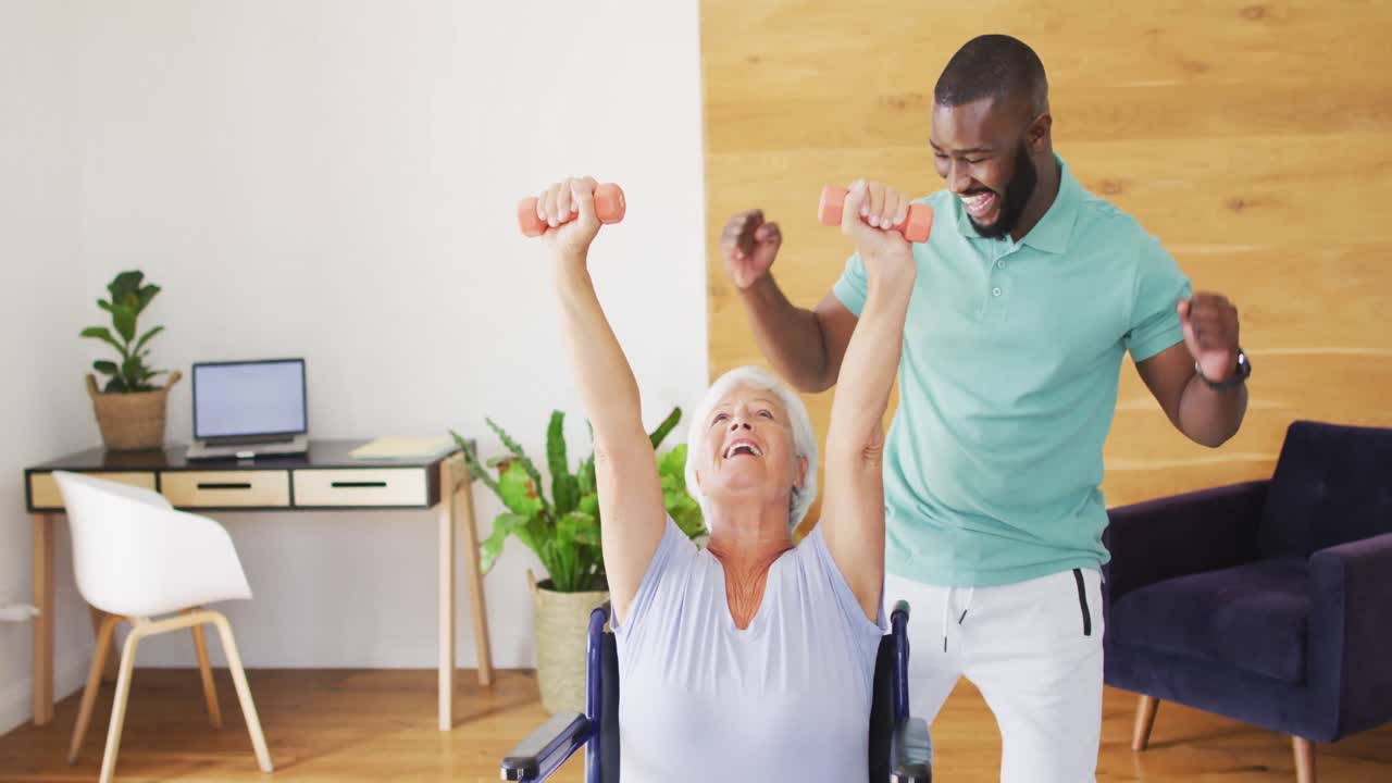 Video of happy african american male physiotherapist exercising with caucasian senior woman