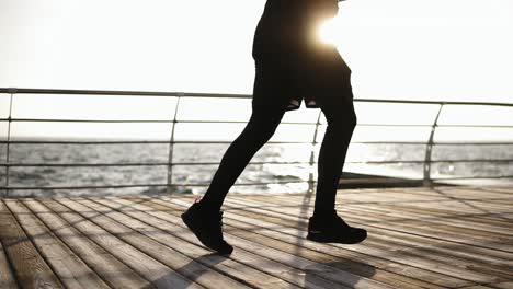 male legs running along the dock near seaside. outdoors footage. sport and recreation.