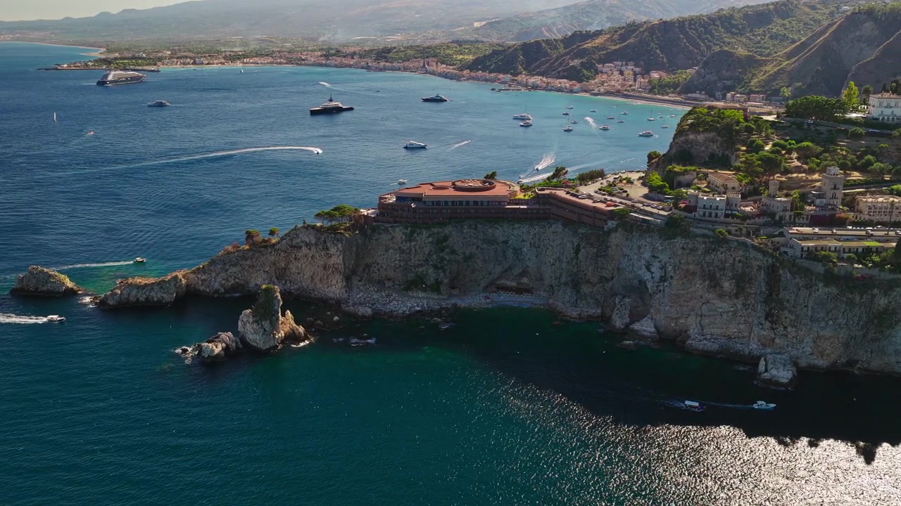 UNAHOTELS Capotaormina - Luxusní hotelový resort na útesu s výhledem na pobřeží v Taormině, Sicílie, Itálie. Letecký záběr
