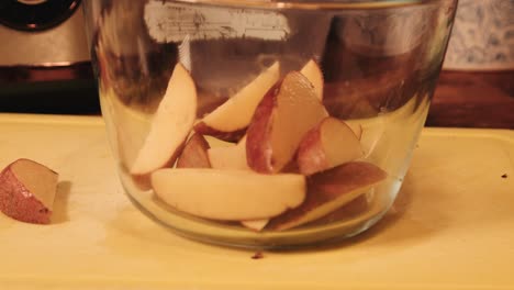 freshly cut raw potato wedges placed into mixing bowl ready for seasoning