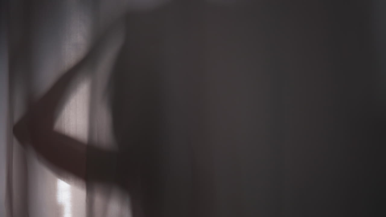 silueta de mujer lavando el cuerpo en la ducha detrás de la cortina. mujer joven disfruta de agua caliente lavando la cabeza. silueta femenina se ducha detrás de una cortina de ducha