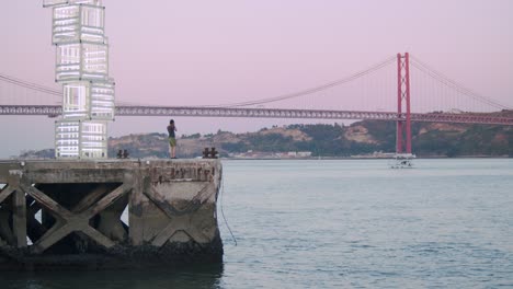 guy takes pictures of view at 25th april bridge in lisbon, portugal