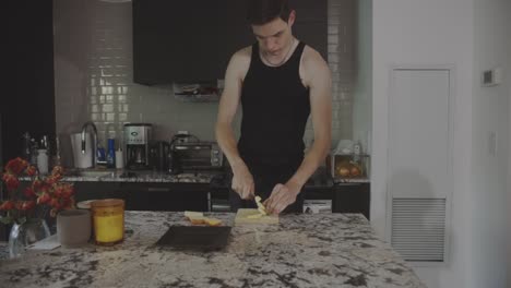 young caucasian man chopping and eating fresh apple fruit on the kitchen countertop