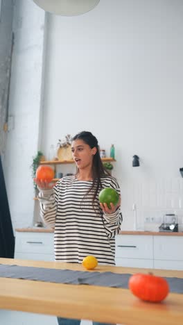 mujer jugando con frutas en una cocina