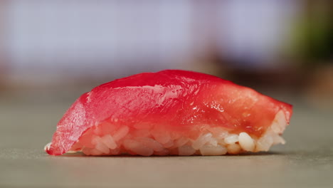 close-up of salmon sushi piece with chopsticks