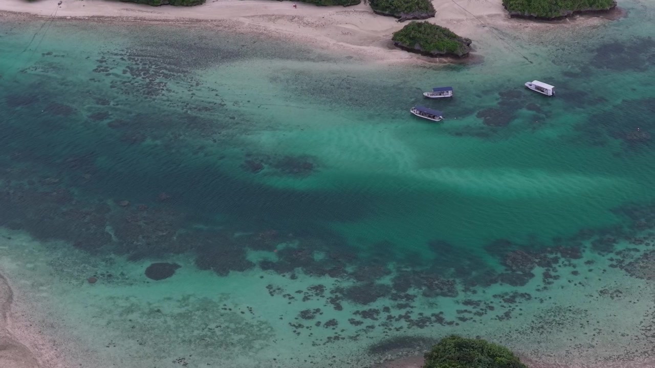 Riprese aeree orizzontali inclinate verso il basso con movimento laterale a destra sopra la laguna turchese e i banchi di sabbia dell'isola di Kojima e della baia di Kabira, isola di Ishigaki, Okinawa, Giappone.