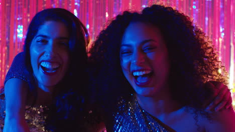 portrait of two women friends having fun dancing in nightclub bar or disco with sparkling lights 1