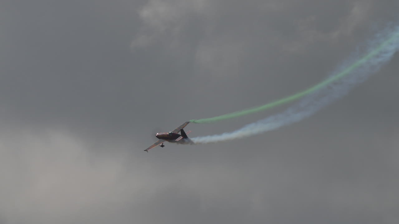 Colorful propeller airplane making a tight turn with smoke trail during acrobatic flying performance