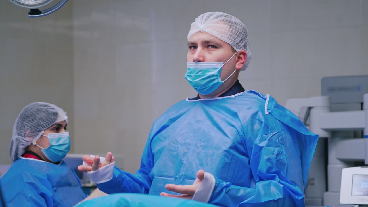 Medical nurse helps doctor to dress sterile clothing. Assistant dresses a surgical gown to a male surgeon in the operating room.