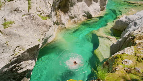 carefree young woman jumping from a cliff to swim