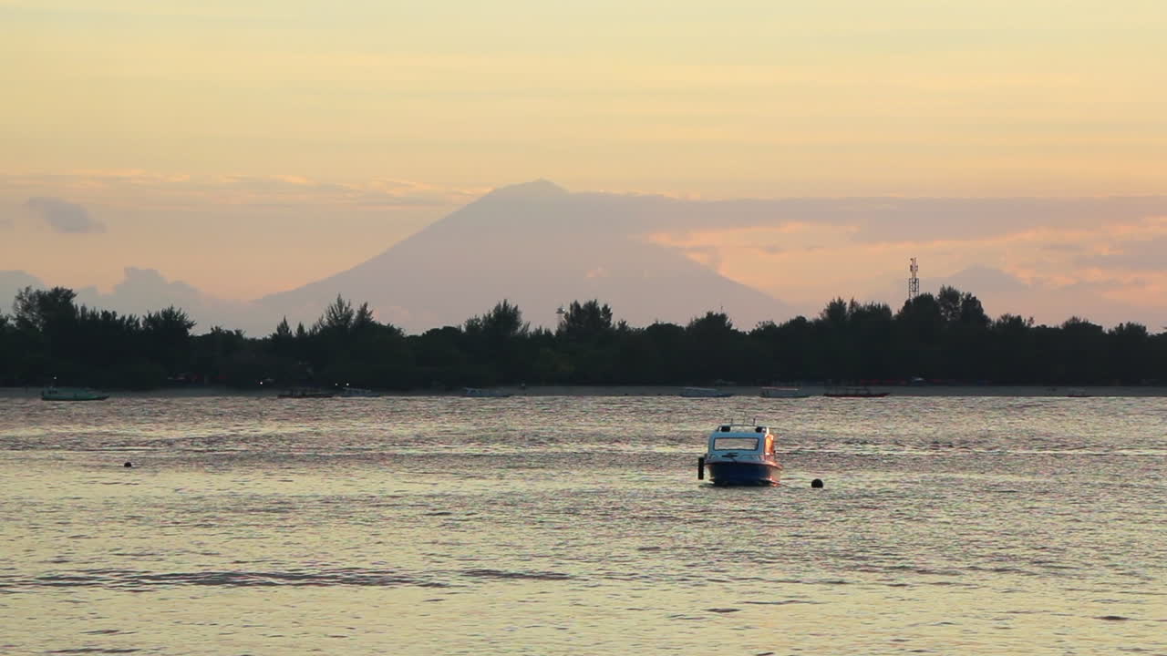 만에 보트가 떠 있는 빈티지 길리 섬 일몰과 배경에 린자니 산