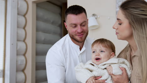 loving caucasian parents and their toddler son sit on the bed. happy family spend time at home together.