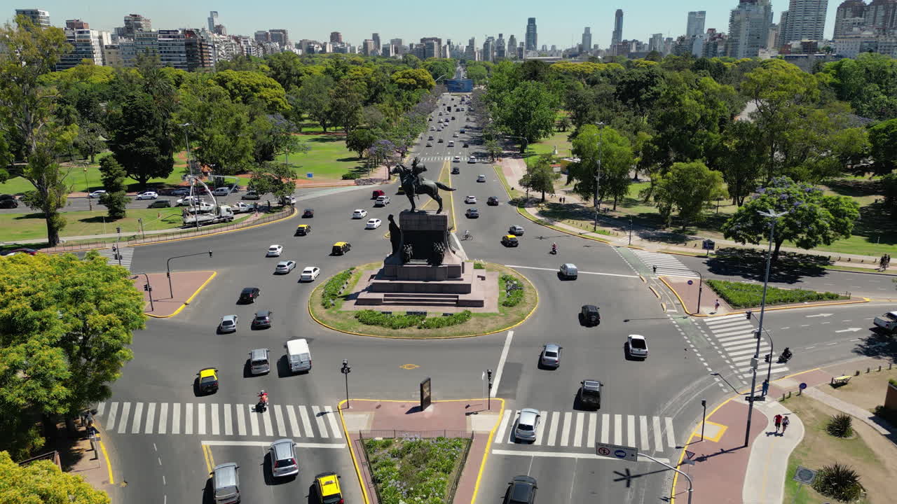 Time-lapse aereo di una trafficata rotatoria cittadina con traffico e un monumento.