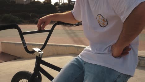 close-up of seated bmx bike rider, the fork and handlebars of his cycle