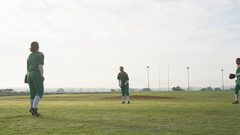multiracial female baseball players catching and throwing the ball on a pitch, copy space