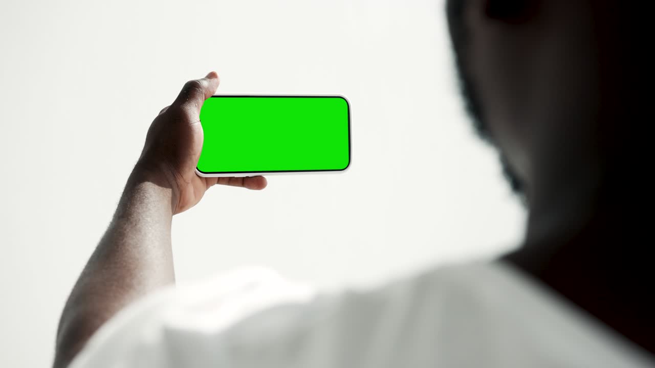 Young Person Use Smartphone with Green Screen Chroma Key Close-up. Guy Look Hold in Hand Cell Phone Mock-up. Concept Watch and Show Internet Social Media, Video Calls, Read News, App, iot, Movie 4k