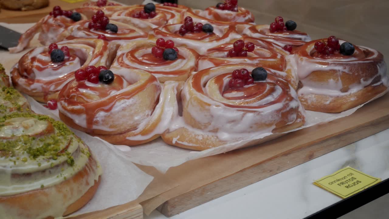 Freshly baked cinnamon rolls with pistachio topping and colorful fruit glaze
