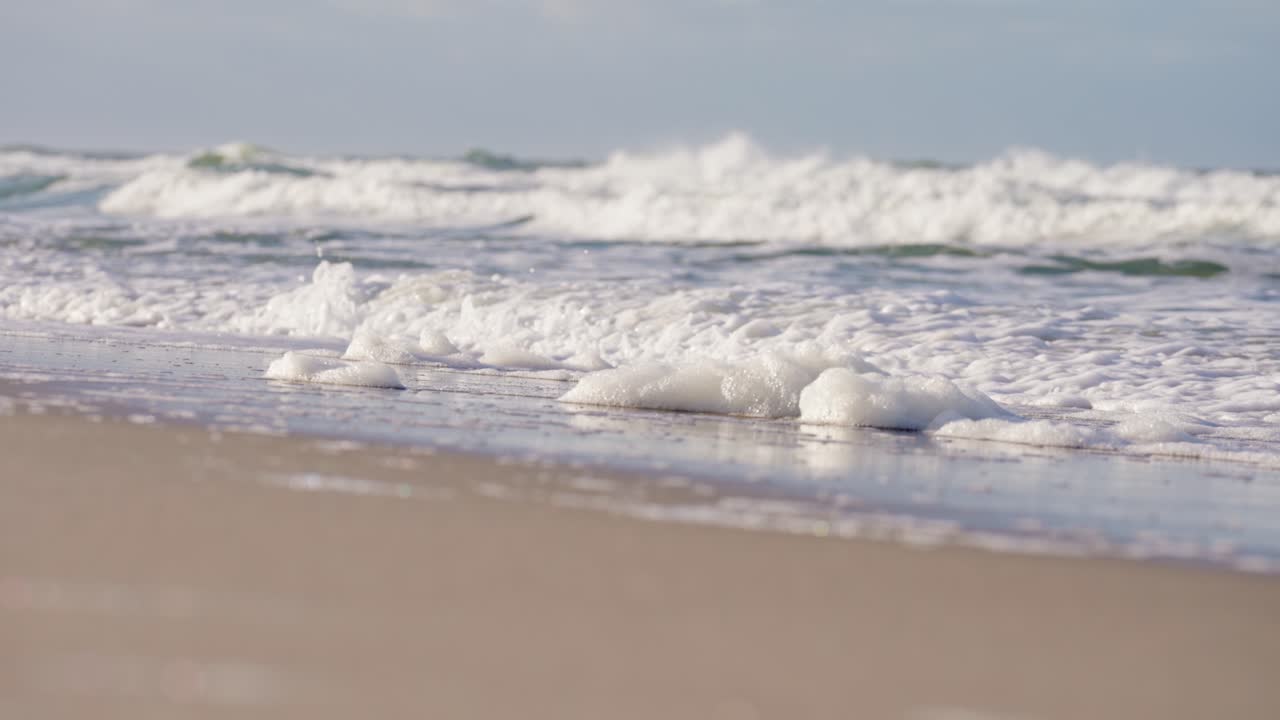 독일의 모래 실트 해변에서 하얀 거품을 씻는 파도 깨기