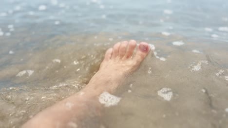 toes in the warm ocean while a wave gently rolls in