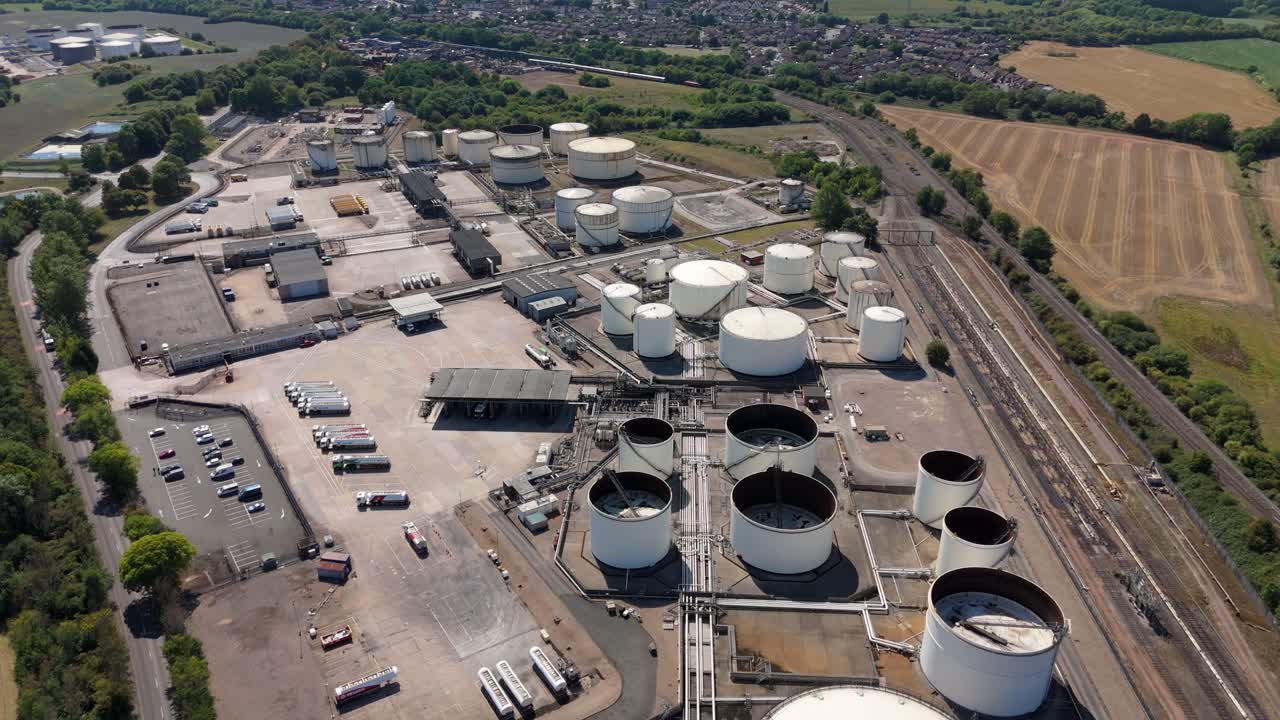 Industrial aerial drone footage of Kingsbury chemical plant with fuel silos and gas energy distribution surrounded by England countryside landscape