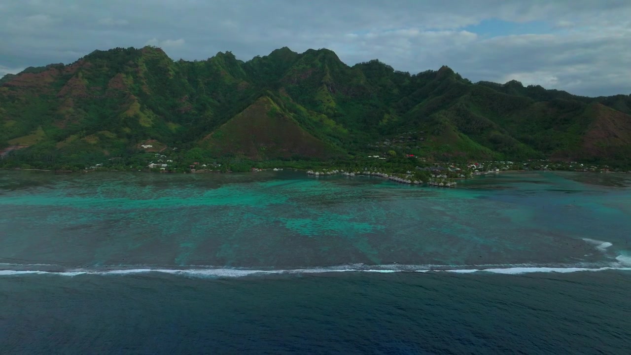 Luftfoto fra drone af Cooks Opunohu Bugt på Moorea-øen, Fransk Polynesien, om morgenen. Både ses i Passe, under klar himmel over lagunen, koralrevet og bølgerne. Bjergene Mauaroa, Tohivea, Rotui og Haapiti ses mod Stillehavet, fanget i fremadgående bevægelse.