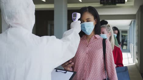 Multi-ethnic-group-working-in-casual-office,-in-face-mask-protecting-from-Covid-19-standing-in-line-