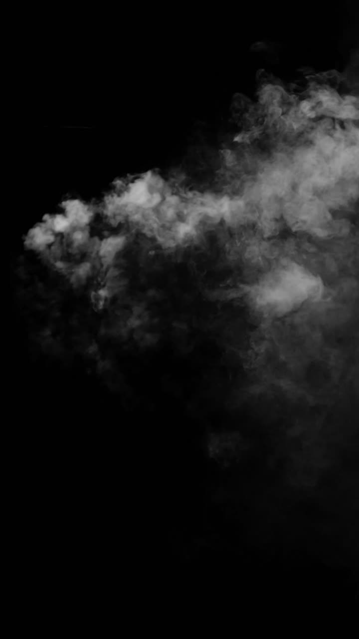 Una realistica nuvola di fumo bianco o nebbia si sposta orizzontalmente nella parte superiore di uno sfondo nero. Una sovrapposizione verticale dinamica per effetti VFX o effetti atmosferici