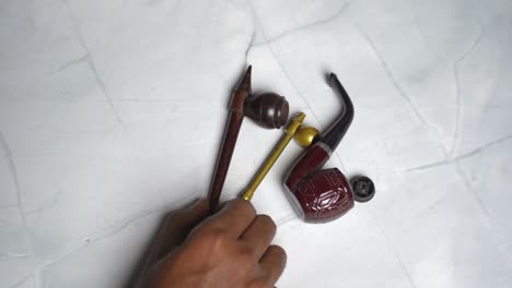 man taking tobacco smoking pipes on table