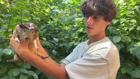 adolescente sosteniendo un conejillo de indias en el jardín
