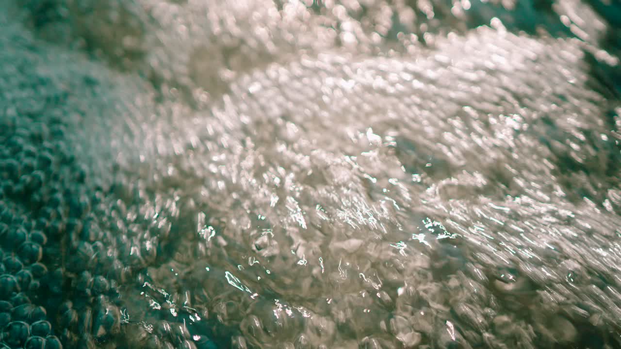Closeup view of fresh water stream gushing air bubbles popping