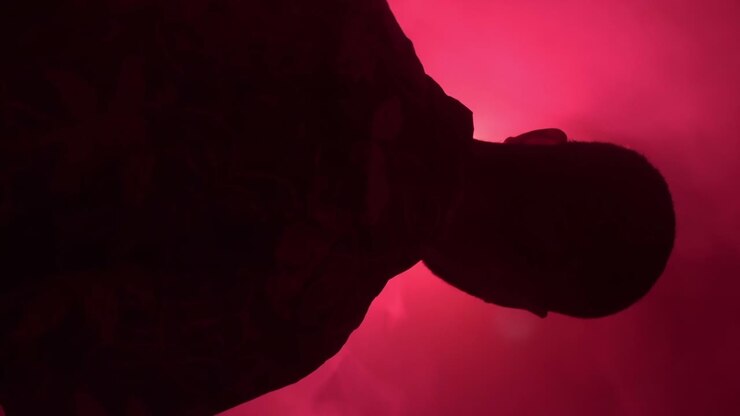 Uomo depresso, concetto astratto, fortemente retroilluminato con luce rossa, verticale