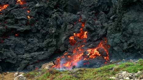 lava flowing from fagradalsfjall volcano slowly burning surrounding landscape in iceland - close up shot