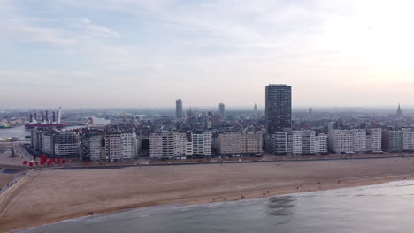 Ostend-City-by-the-North-Sea,-Belgium,-Aerial-Pullback-Above-the-Beach